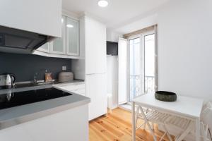uma cozinha com armários brancos, uma mesa e uma janela em FLH Mouraria Charming Flat II em Lisboa