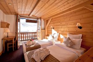 a bedroom with two beds in a wooden room at Hotel les Flocons in Courchevel