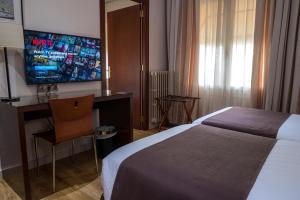 een hotelkamer met een bed, een bureau en een televisie bij Ramon Berenguer IV in Lleida