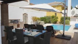 a table with chairs and an umbrella next to a pool at VILLA AMANECER in Almuñécar