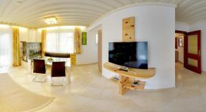 sala de estar con TV, mesa y sillas en Karglhof Bungalows en Faak am See