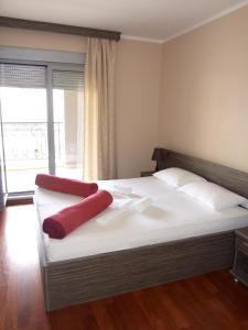 Una cama con dos almohadas rojas encima. en Beachfront Apartments Oaza 2, en Petrovac na Moru
