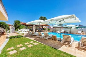 een patio met stoelen en parasols naast een zwembad bij Hesperides Hotel Pefkochori in Pefkochori