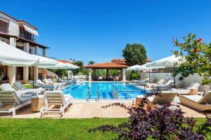 a swimming pool with lounge chairs and umbrellas at Hesperides Hotel Pefkochori in Pefkochori