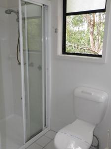 a bathroom with a shower and a toilet and a window at Boatshed in Point Lookout