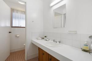 a white bathroom with a sink and a mirror at Eyrie in Point Lookout