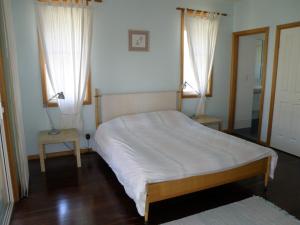 una camera con un letto e due finestre con tende bianche di 11 Bambara Street a Point Lookout