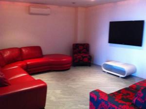 ein Wohnzimmer mit einem roten Sofa und einem Flachbild-TV in der Unterkunft Azul del Mar in Point Lookout