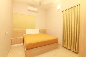a bedroom with a yellow bed in a room at Castilo Inn Hotel Apartments in Cochin