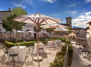 un groupe de tables et de chaises avec parasols dans l'établissement Relais & Chateaux Palazzo Seneca, à Norcia