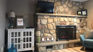 Four Cedars Accommodation في جاسبر: غرفة معيشة مع موقد حجري مع تلفزيون