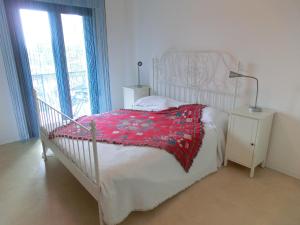 una camera con un letto bianco e una coperta rossa di Residence Tintoretto a Lignano Sabbiadoro