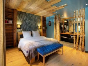 1 dormitorio con 1 cama grande y pared azul en Chalet 1703 - Open Living Hotel & Spa, en Le Petit-Bornand-lès-Glières