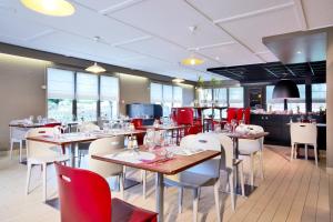 a restaurant with wooden tables and chairs and red chairs at Campanile Vierzon in Vierzon