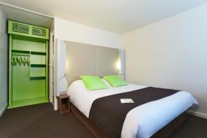 a bedroom with a large bed with two green pillows at Campanile Vierzon in Vierzon