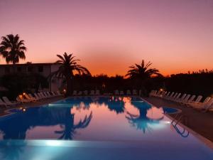 a pool with chairs and a sunset in the background at Villaggio Alba Chiara in Vieste