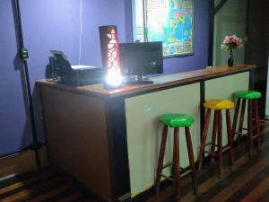 a bar with two green stools and a computer at Lapa Casa Hostel in Rio de Janeiro