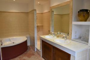 bagno con 2 lavandini, vasca e specchio di Residence le Petit Paradis a Labastide-Rouairoux