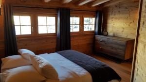 een slaapkamer met een bed en ramen in een hut bij Chalet l'Ardoisière in Villard-Reculas