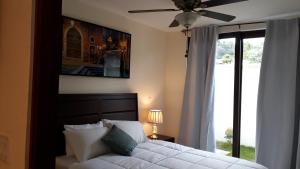 1 dormitorio con 1 cama, ventilador de techo y ventana en Mirango Apartments en Boquete