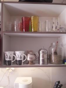 un estante lleno de tazas y otros artículos de vidrio en Aguilar House Hostel B&B en El Calafate