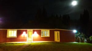 uma pequena casa à noite com a lua atrás dela em Aguilar House Hostel B&B em El Calafate