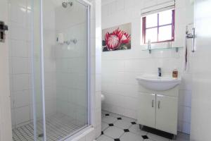 a white bathroom with a shower and a sink at 12 On Oyster in Durban
