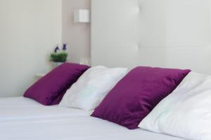 two purple pillows sit on a white bed at O balcón da ribeira in Parada del Sil