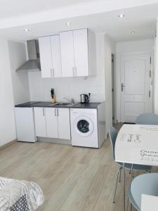 uma cozinha branca com uma máquina de lavar roupa e uma mesa em estudio habaneras em Torrevieja