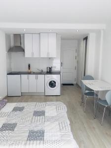 uma cozinha com armários brancos e uma mesa com cadeiras em estudio habaneras em Torrevieja
