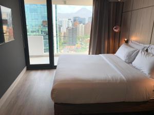 a large bed in a hotel room with a large window at One Nk Apartments in Santiago