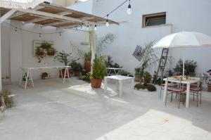 eine Terrasse mit Tischen, Stühlen und einem Sonnenschirm in der Unterkunft A Casa di Mich in Monteroni di Lecce