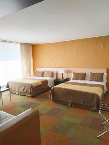 a hotel room with two beds and a large window at Hotel Alborada in Concepción