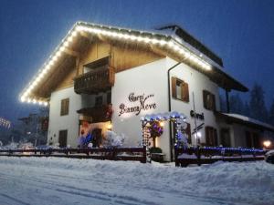 a building with lights on it in the snow at Garni Biancaneve Ruffrè-Mendola in Mendola