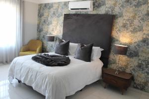 Schlafzimmer mit einem großen weißen Bett mit einem schwarzen Kopfteil in der Unterkunft Prisatt Boutique Hotel in Onverwacht