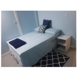 Dormitorio azul con cama y mesa pequeña en Careffe Suites Unit 4, en Cap Estate