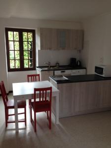 a kitchen with a white table and two red chairs at Appart dans fermette in Audeville