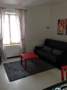 a living room with a black couch and a red stool at Appart dans fermette in Audeville