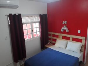 a bedroom with a bed with a red wall at Pousada e Hostel Boneca de Pano in Maceió