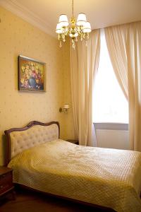 a bedroom with a bed with a chandelier and a window at V.I.P.Apartmens Rynok Sqr.19 in Lviv