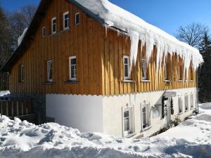 a house covered in snow with icicles hanging from it at Dukát Kořenov in Kořenov