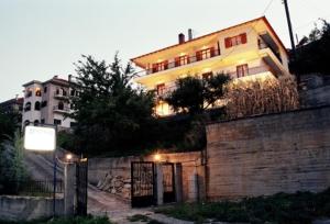 a building on a hill next to a brick wall at Guesthouse Ahillion in Nestórion