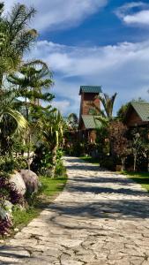 un chemin de terre menant à une maison plantée de palmiers dans l'établissement Cabañas la finca 2, à Atlixco