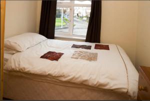 Una cama con sábanas blancas y una ventana en una habitación en killowen en Dublín