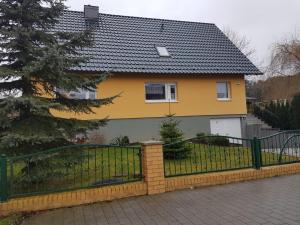 a yellow and grey house with a fence at Fuchsbau in Schwedt