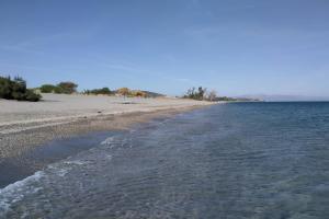 an empty beach with umbrellas and the ocean at Ktima Petalea in Gythio