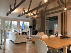a living room with a wooden table and white chairs at Country House by the lake in Hästveda