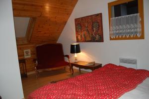 1 dormitorio con 1 cama roja y 1 silla en L'Ardalh en Louvie Juzon