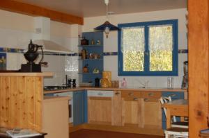 una cocina con armarios azules y una ventana en L'Ardalh en Louvie Juzon