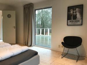 a bedroom with a bed and a chair and a window at Country House by the lake in Hästveda